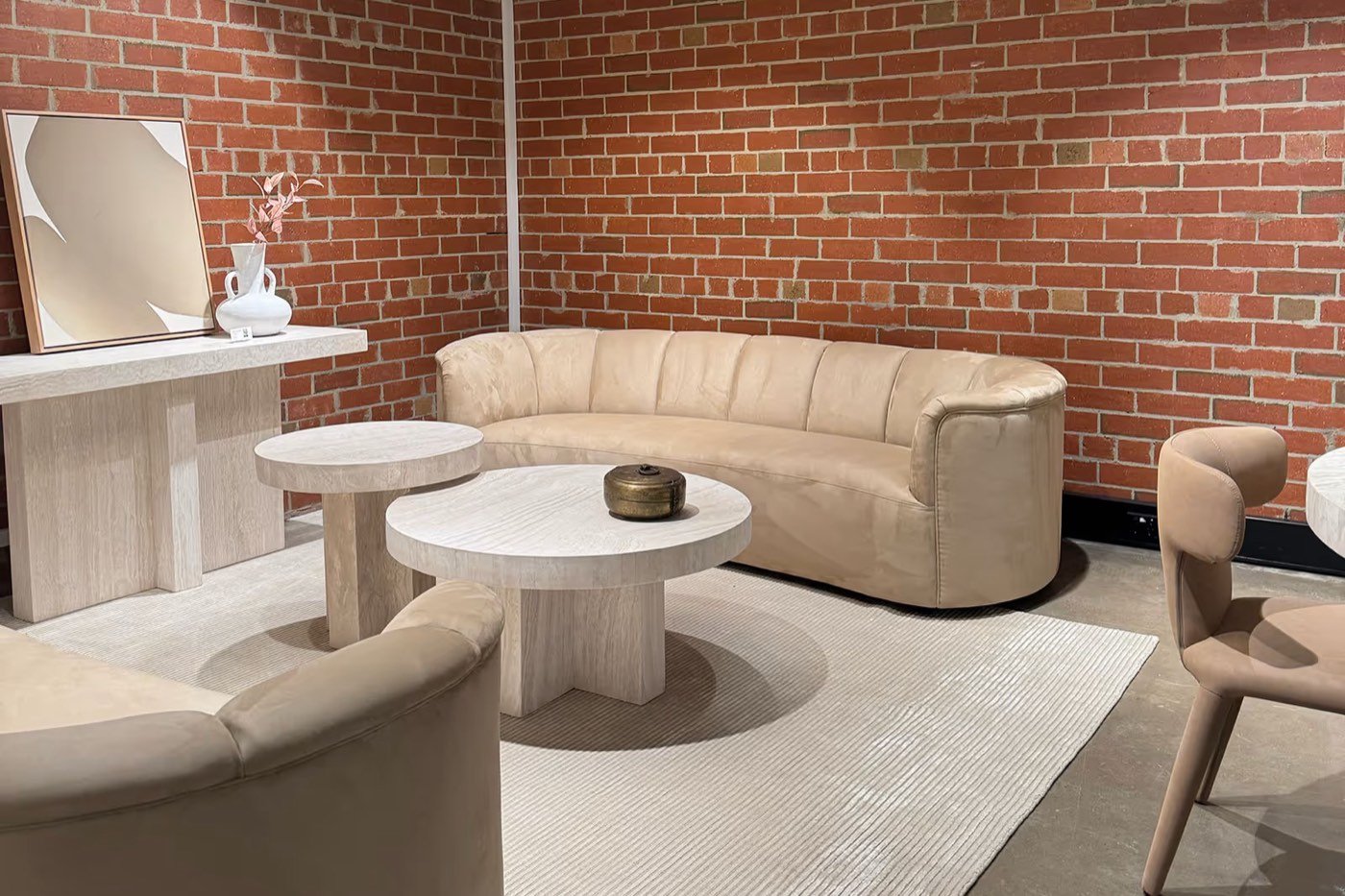 Curved cream sofas against a red brick wall at Casa Blanco, Cremorne